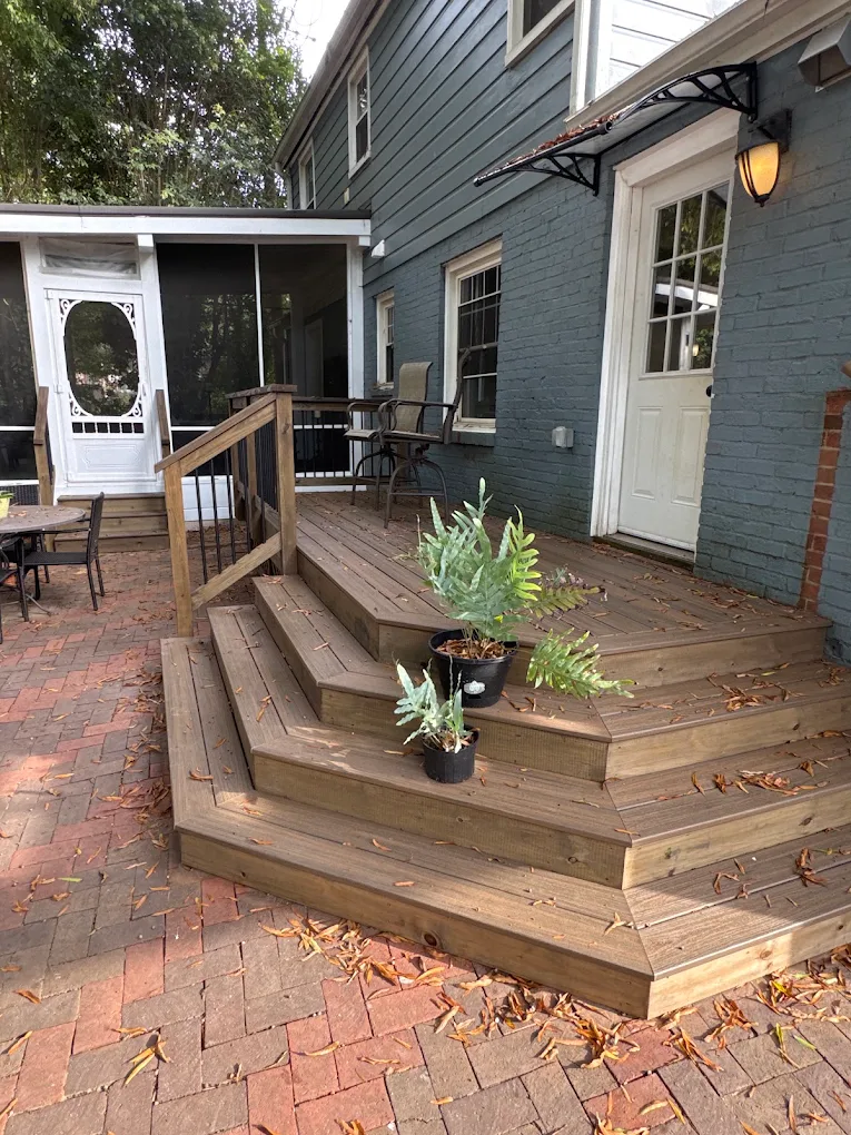 Wraparound wood deck steps leading down to a brick patio